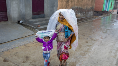 A woman and child walking in the rain in India.