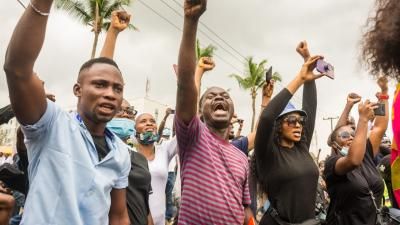 Nigerian protestors pictured shouting with fists raised in the air