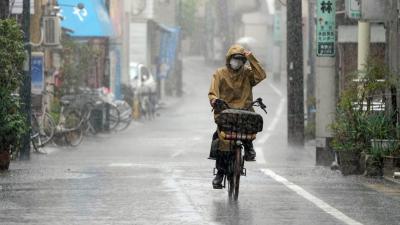 Japanese man wearing a rain coat and riding a bike in heavy rain