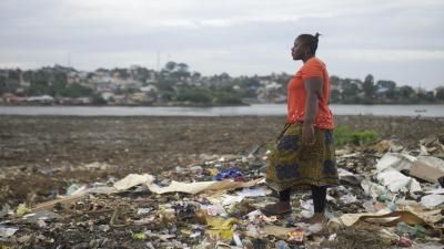 Woman walking in landscape full of rubbish