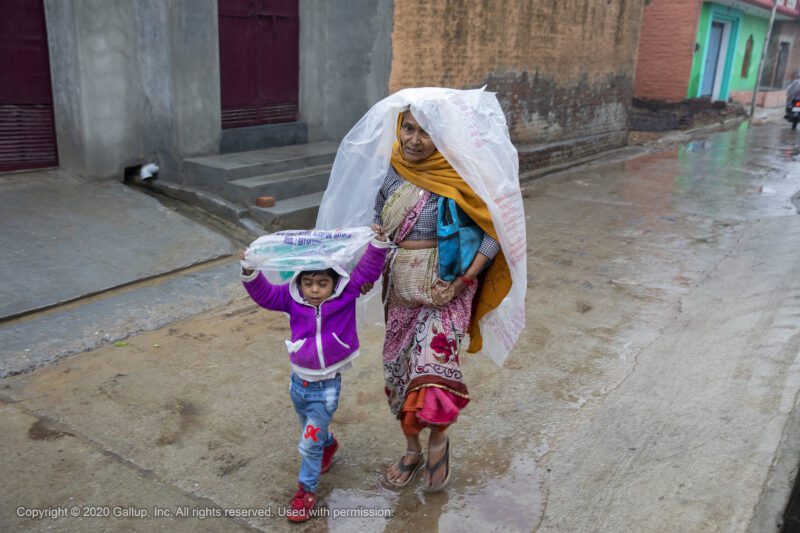 Woman and child walking in the rain in India